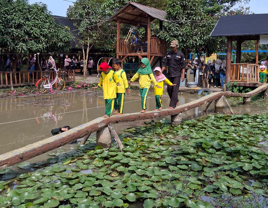Anak-anak berjalan di jembatan kayu di area edukasi air